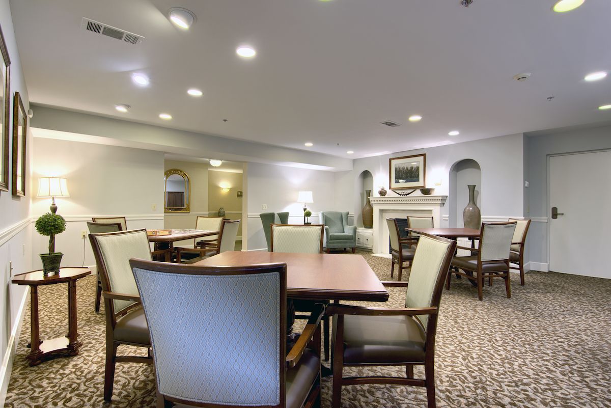 A well-lit dining area featuring tables and chairs, with a cozy fireplace in the background.