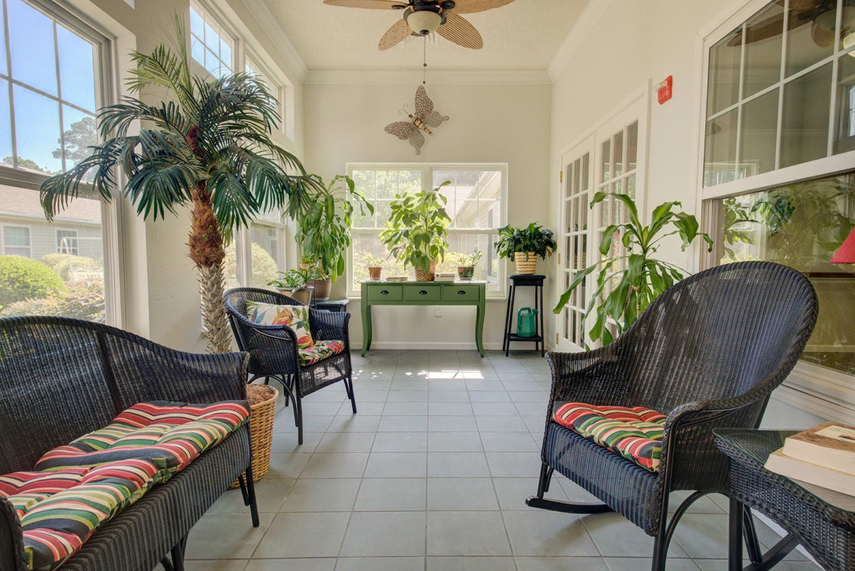 A bright sunroom with rattan furniture and lush indoor plants basking in natural light.
