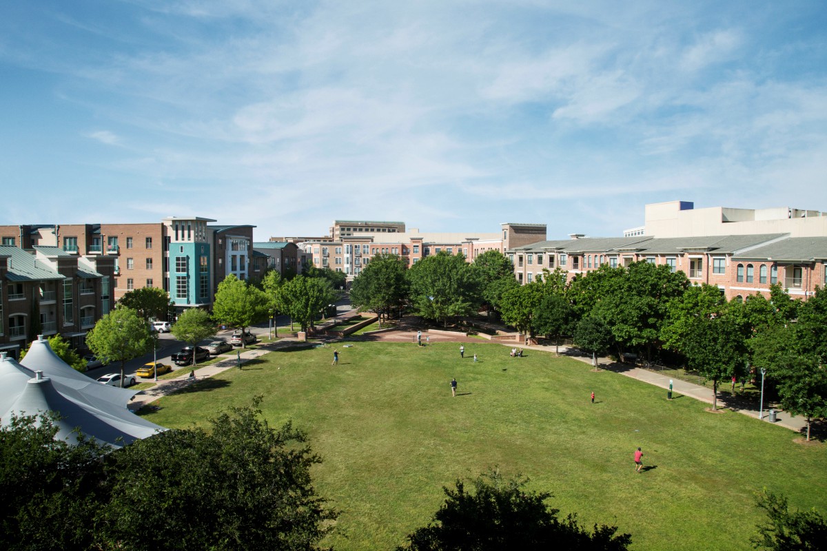 A scenic view of a city park surrounded by buildings under a clear sky.