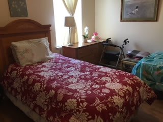 A cozy bedroom with a floral bedspread and a walker nearby.