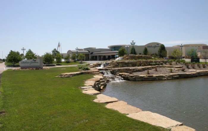 A scenic view of a park featuring a pond and small waterfall surrounded by green grass.