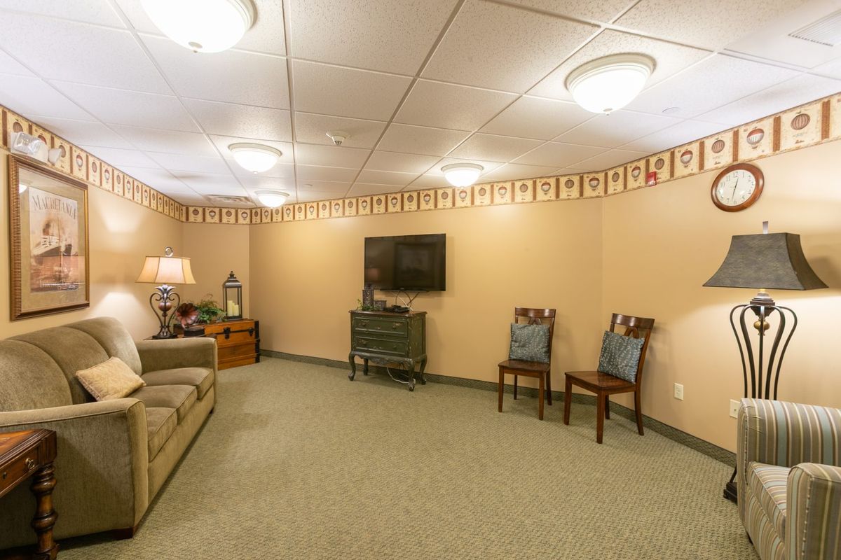 A cozy living room with a sofa, chairs, and a television on the wall.