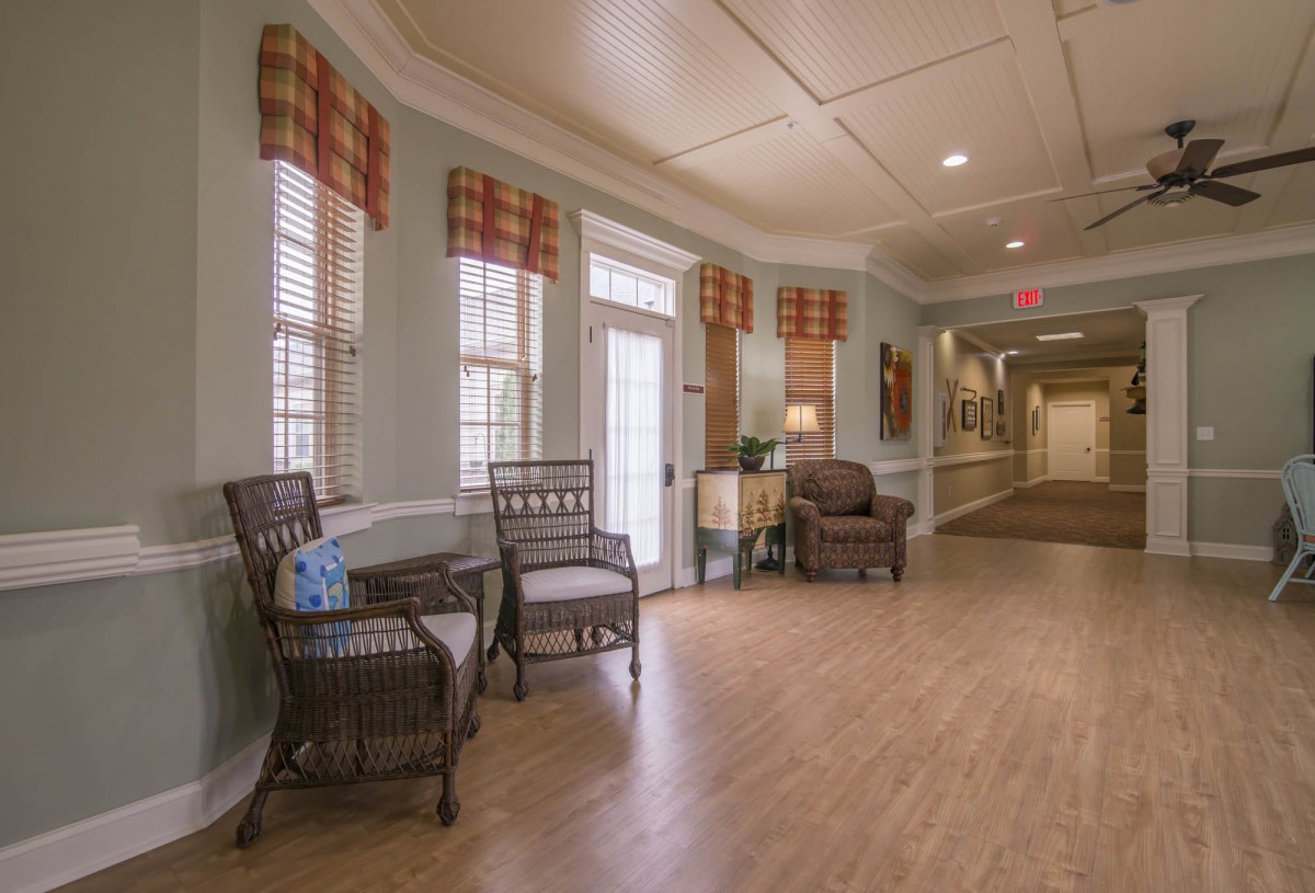 A cozy hallway with chairs and lamps along a wooden floor.