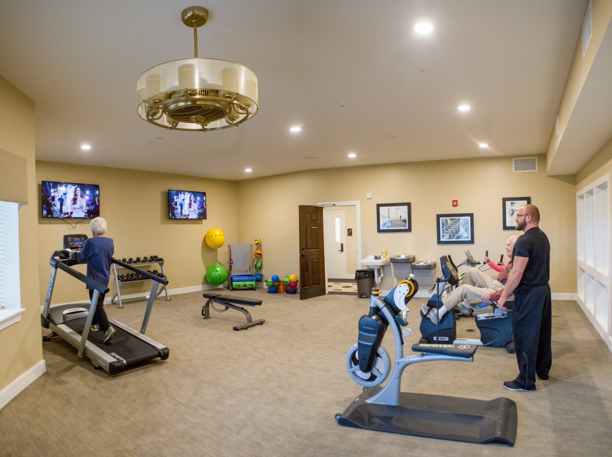 People exercising in a gym with various fitness equipment.