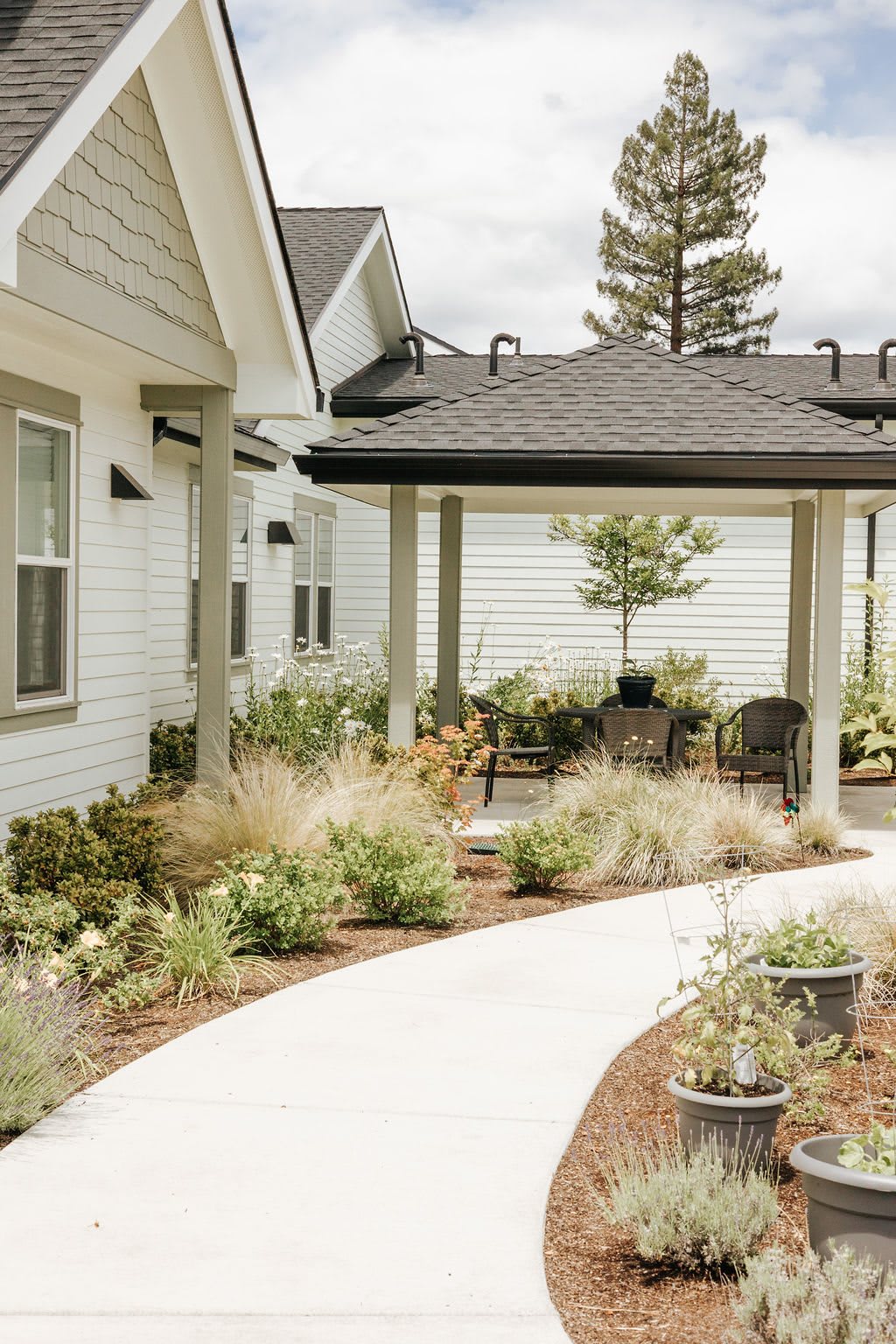 A well-landscaped exterior view of a house featuring a patio, walkway, and surrounding garden.