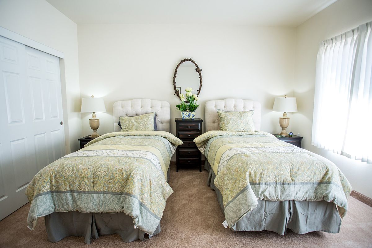 A cozy bedroom with twin beds, featuring elegant decor and a classic mirror.