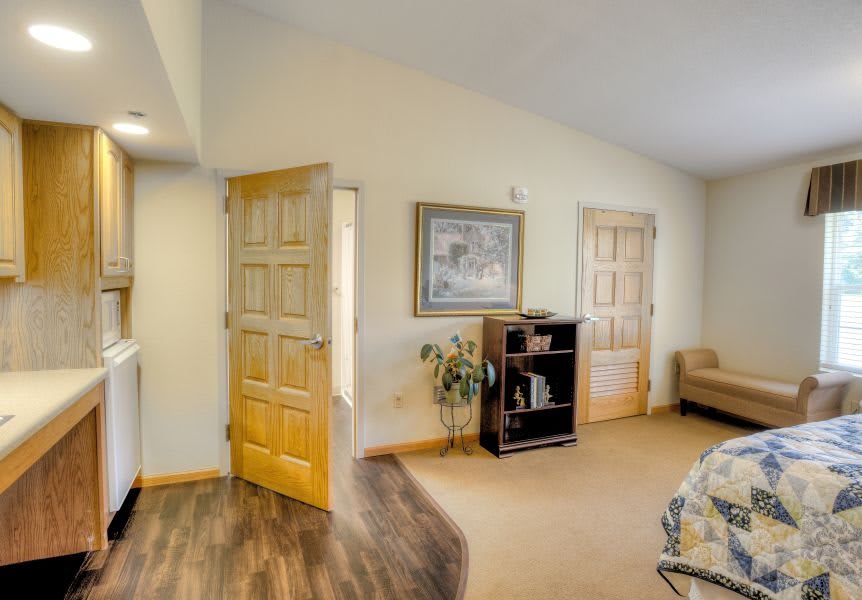 A cozy living room with wooden doors, a shelf, a sofa, and decorative paintings.