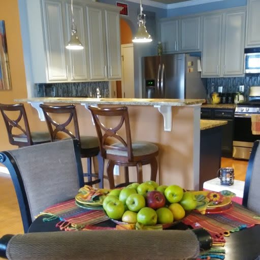 A cozy kitchen and dining area featuring a bowl of apples on the table and stylish counter stools.