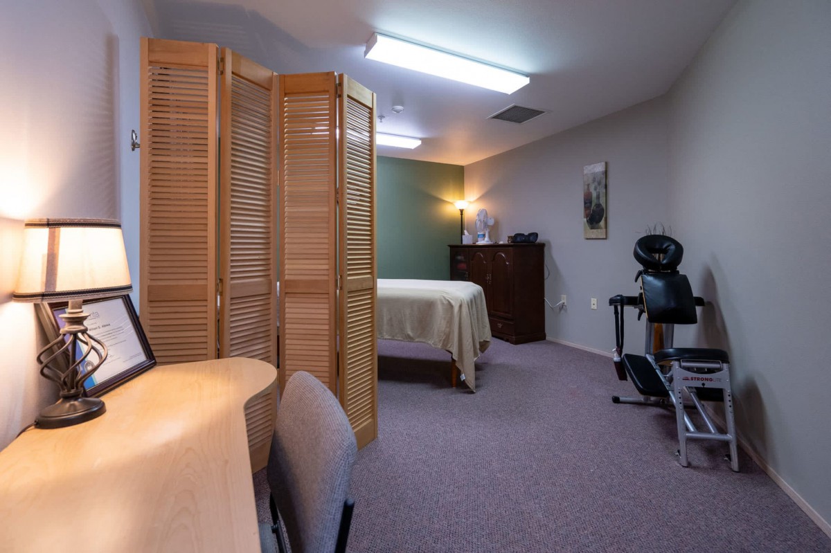 A cozy massage room with a privacy screen and soft lighting, perfect for relaxation.