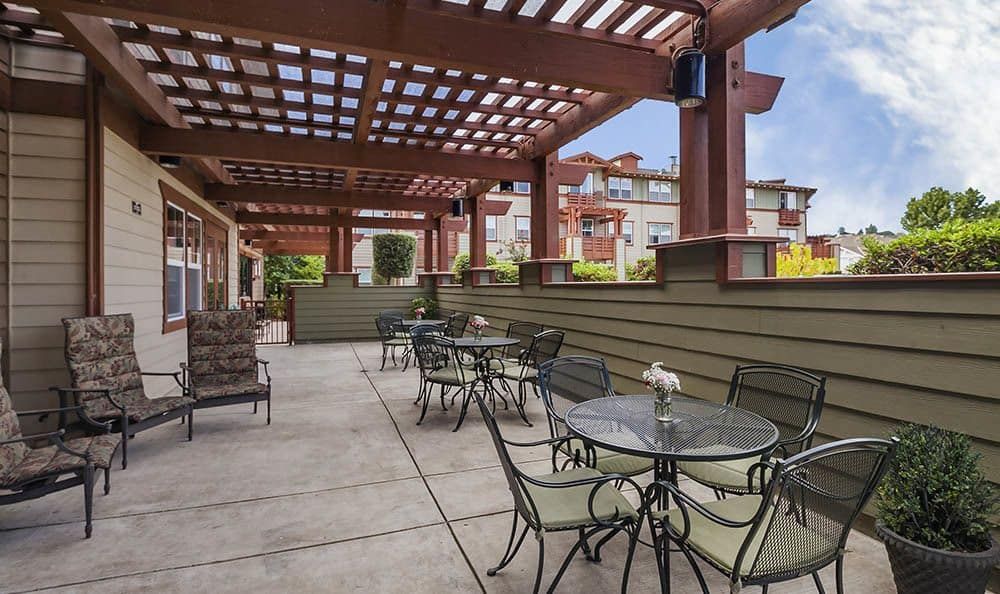 An inviting outdoor patio with tables and chairs under a pergola, perfect for dining in an urban setting.