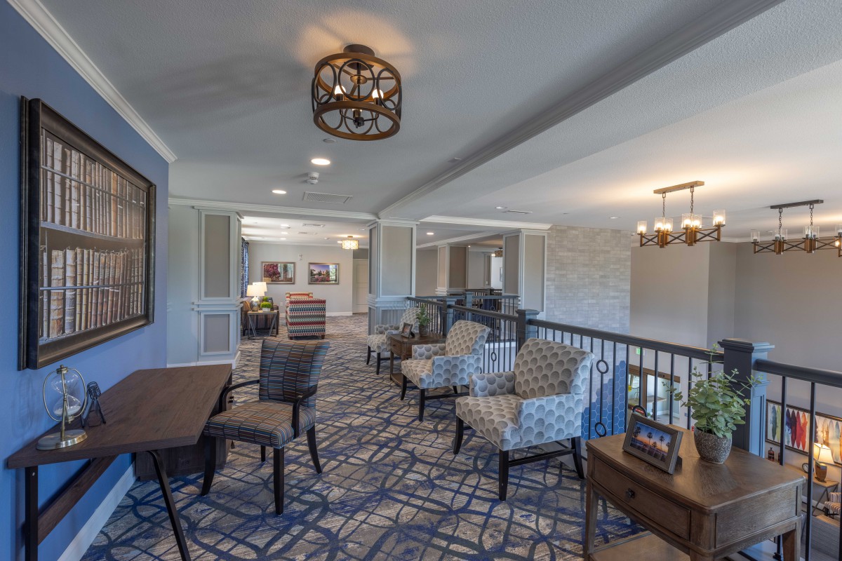 A comfortable and stylish lounge area featuring patterned chairs, a table, carpeted flooring, and elegant light fixtures.