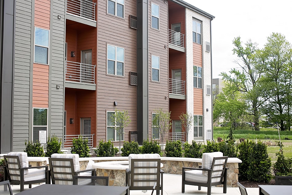 Modern apartment building with outdoor seating and landscaped surroundings.