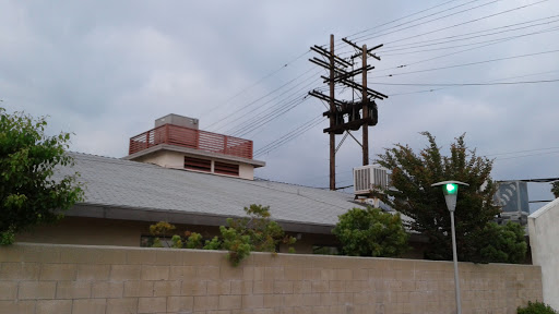An urban scene featuring a building with power lines overhead against a cloudy sky.