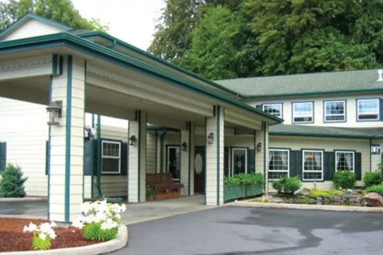 A building entrance with a covered driveway and surrounding greenery.