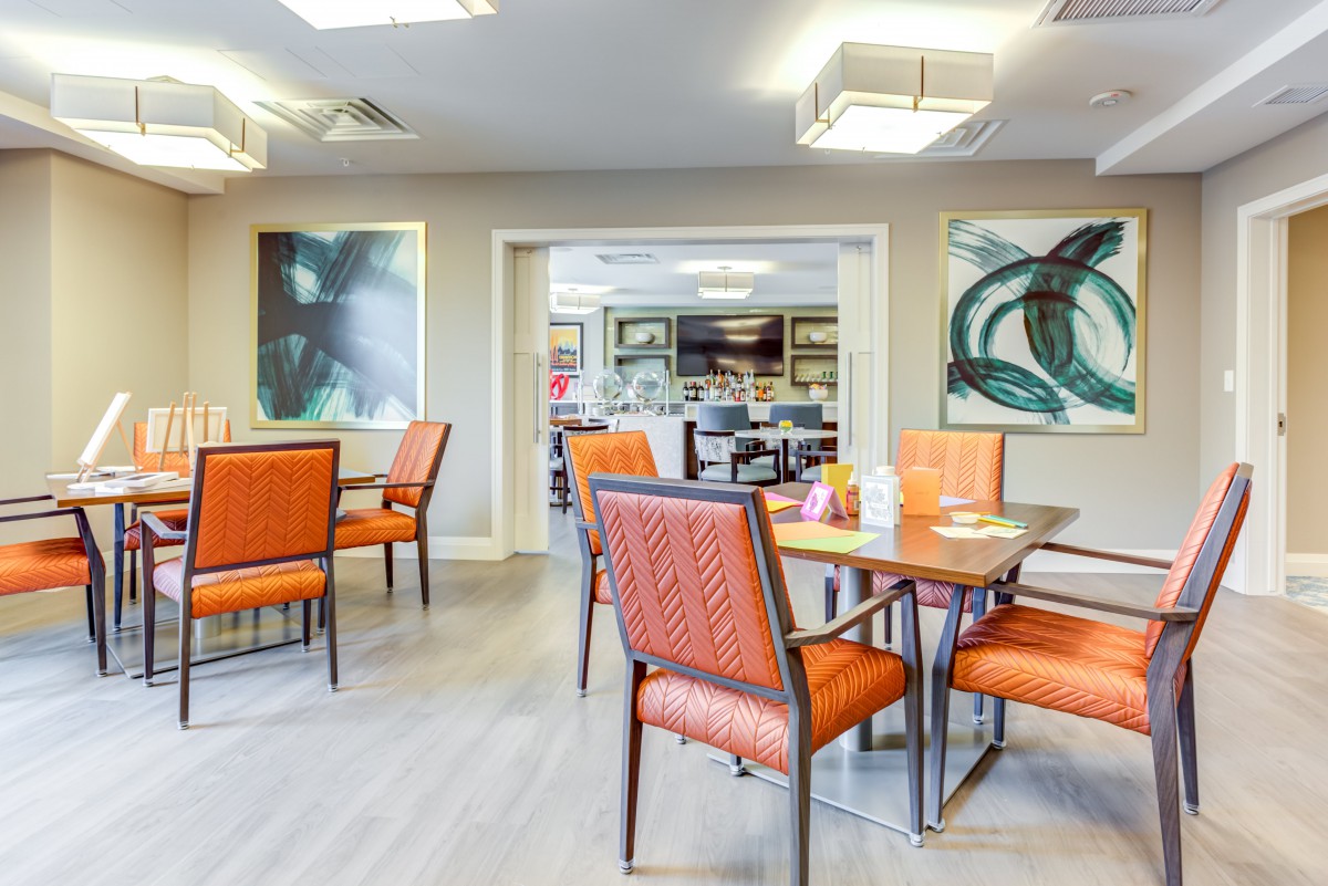 A modern dining area with orange chairs and contemporary artwork on the walls.
