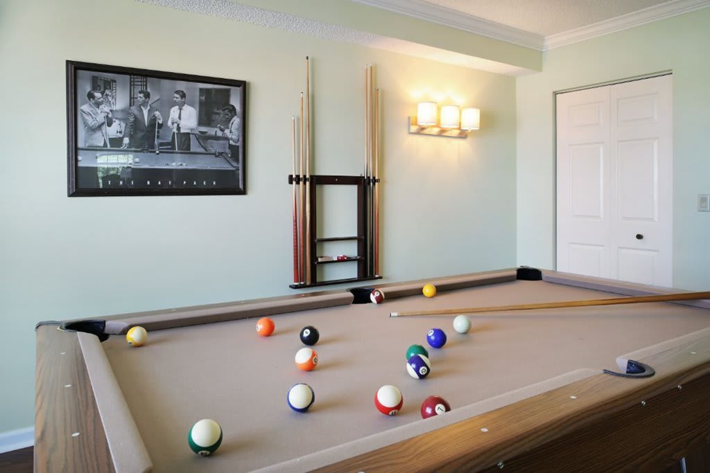 A stylish game room featuring a pool table with balls and cues ready for a match.