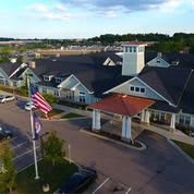 Aerial view of a large building with a flag in the foreground and surrounding landscape.