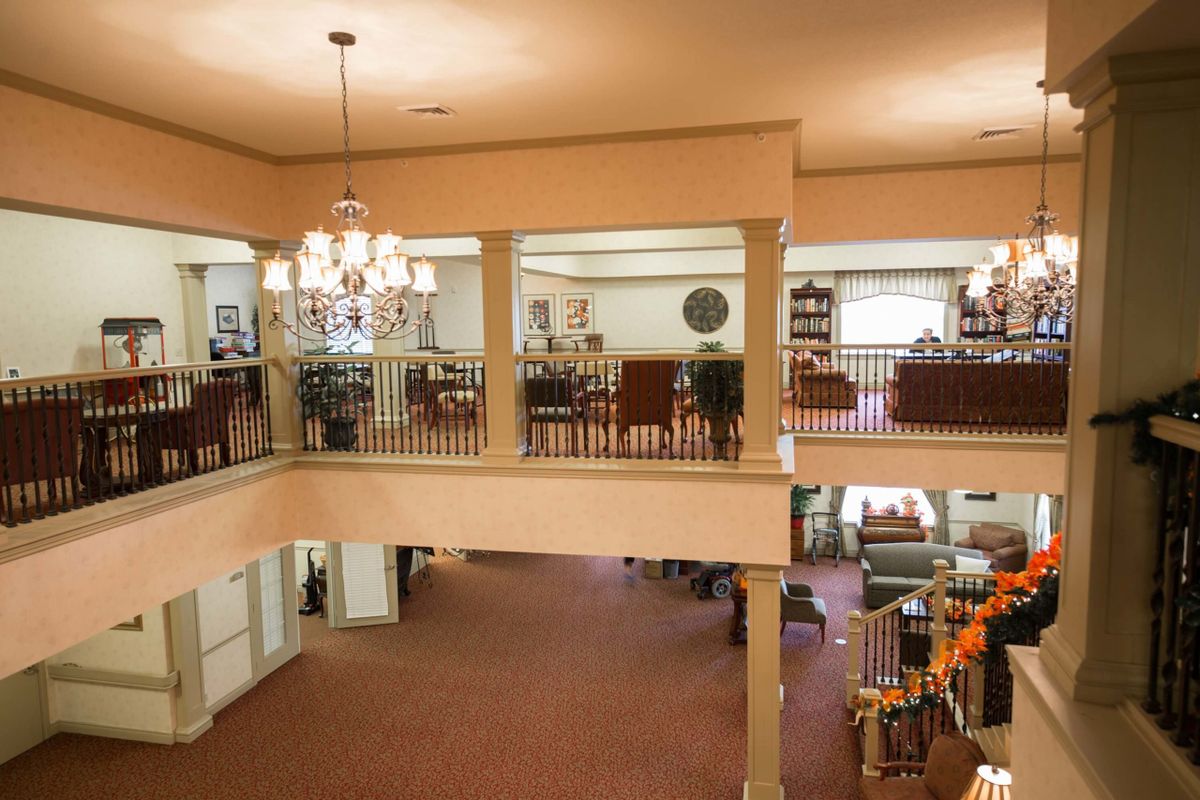 Spacious lobby with a chandelier and upper-level balcony seating area.
