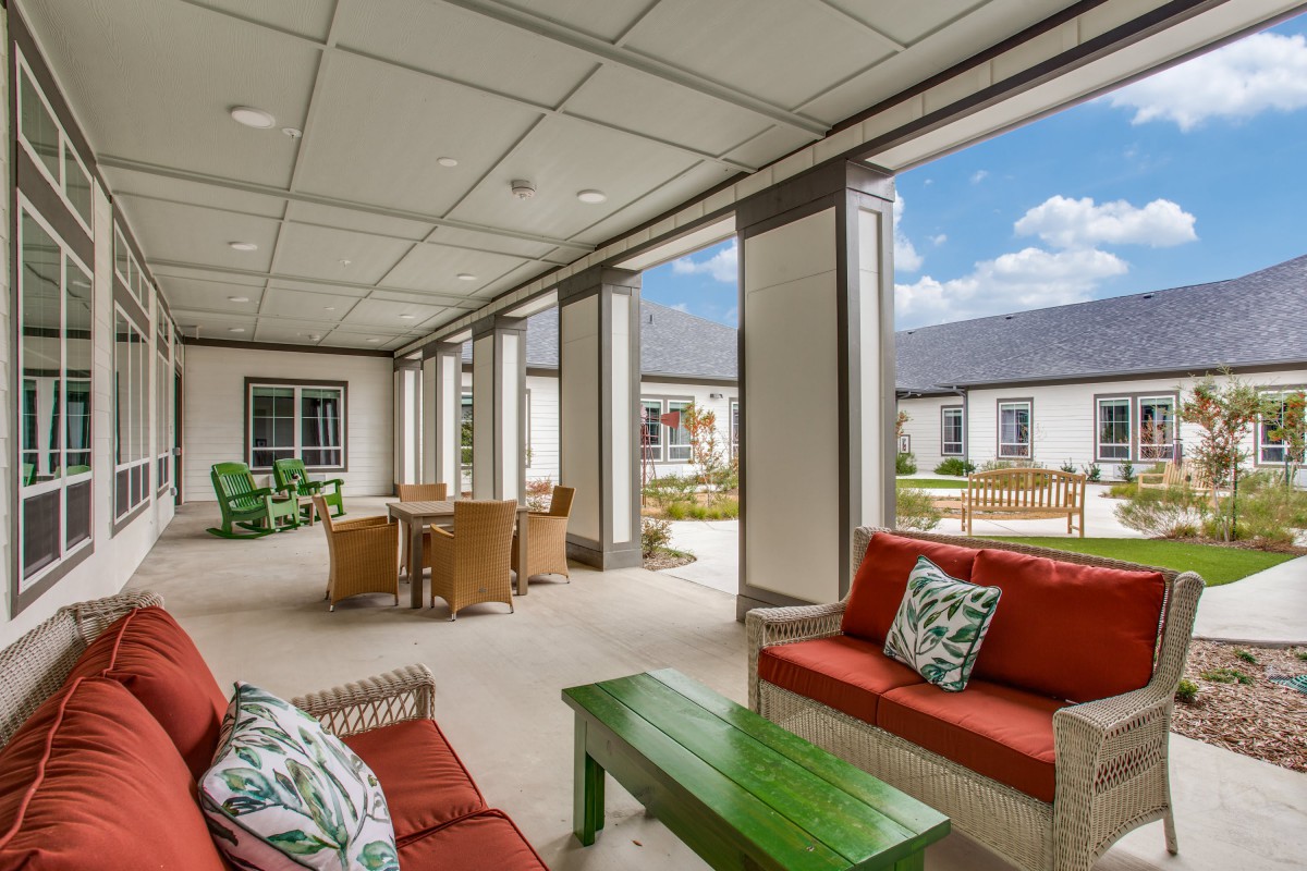 A covered outdoor patio with comfortable seating and tables, ideal for relaxation.