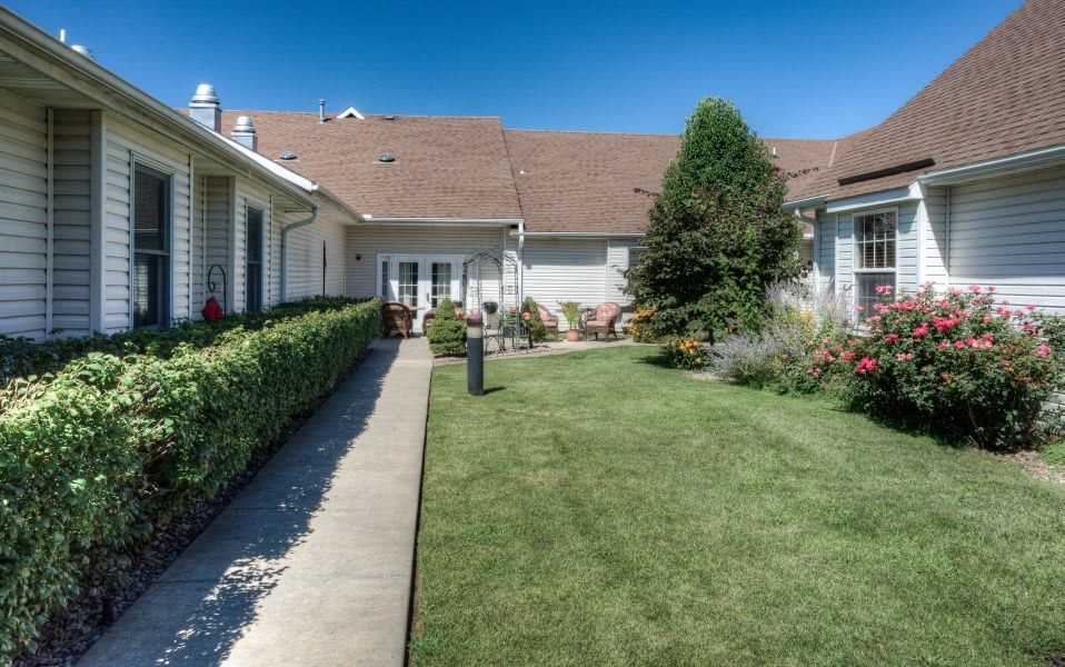 A well-maintained backyard with a lush lawn and garden landscaping under a clear blue sky.