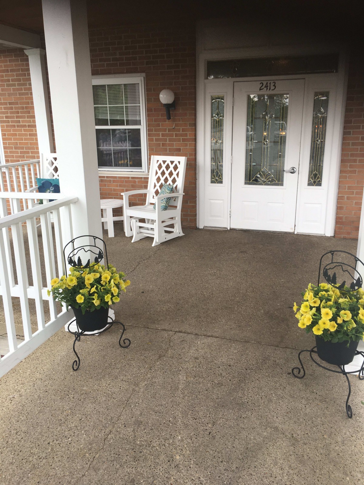 A welcoming front porch with rocking chairs and potted yellow flowers.