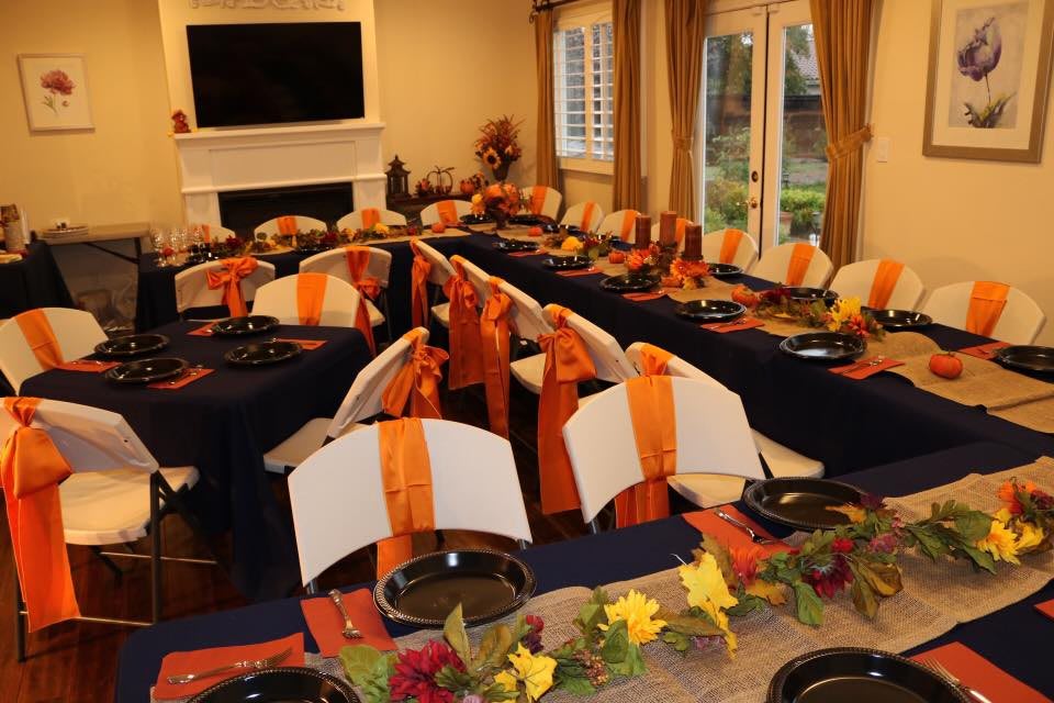 A beautifully set dining room table with fall-themed decorations in orange and black.