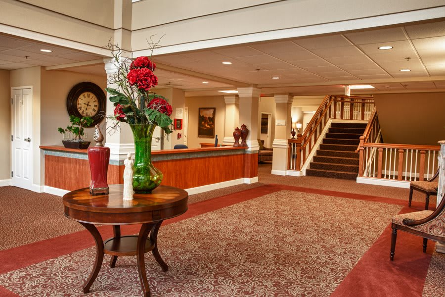 A well-appointed lobby featuring a central table with a flower arrangement and a staircase in the background.