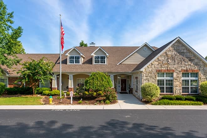A stone and brick building with a flagpole in the front yard, set against a blue sky.