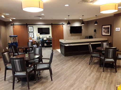 A modern lounge area featuring tables, chairs, and a reception desk.