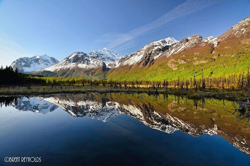 A breathtaking view of majestic mountains reflected in a tranquil lake under a clear blue sky.