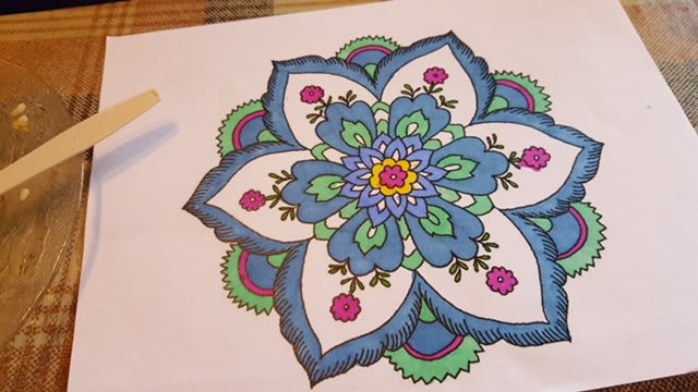 A vibrant mandala design featuring blue, green, and pink colors.