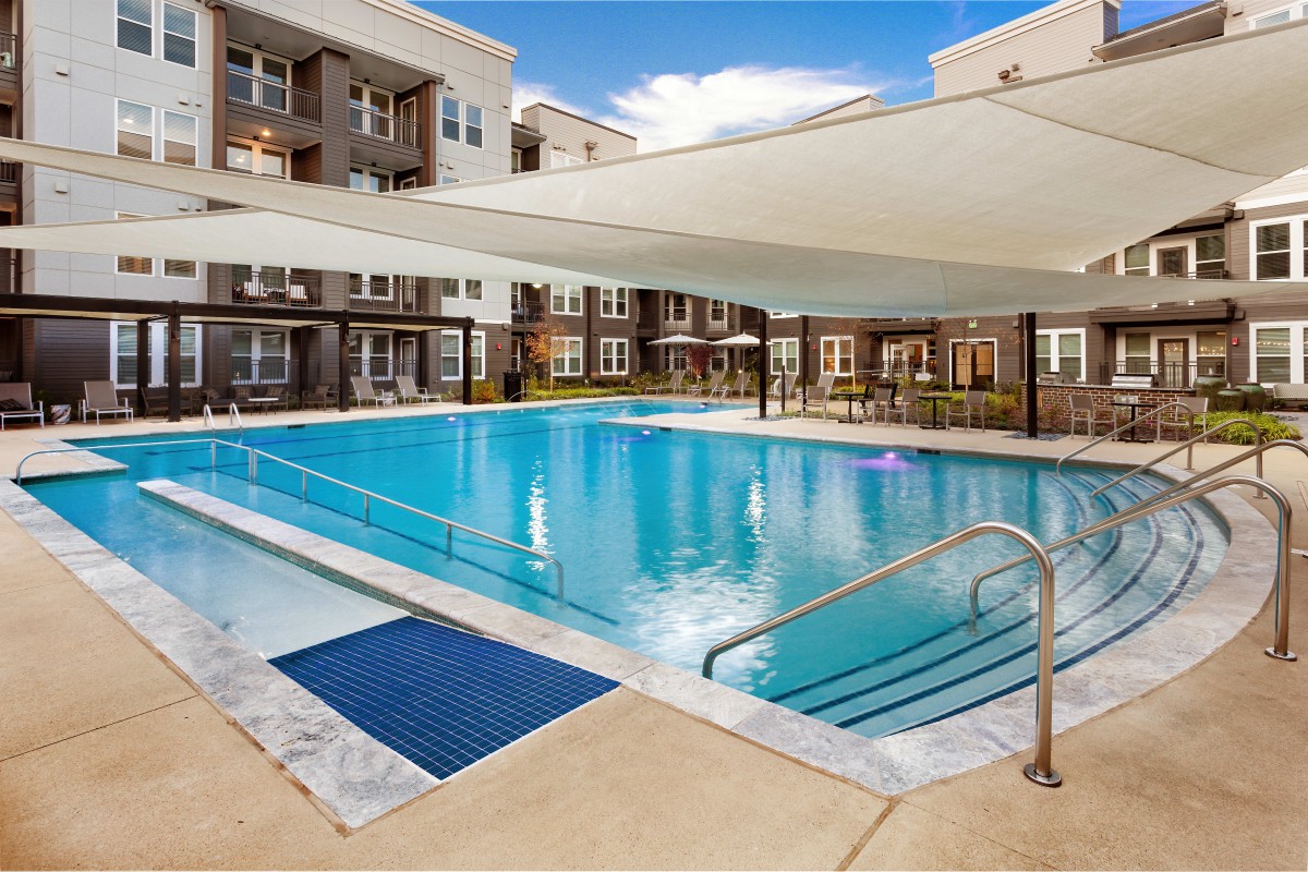 Outdoor swimming pool at an apartment complex with a shade canopy.