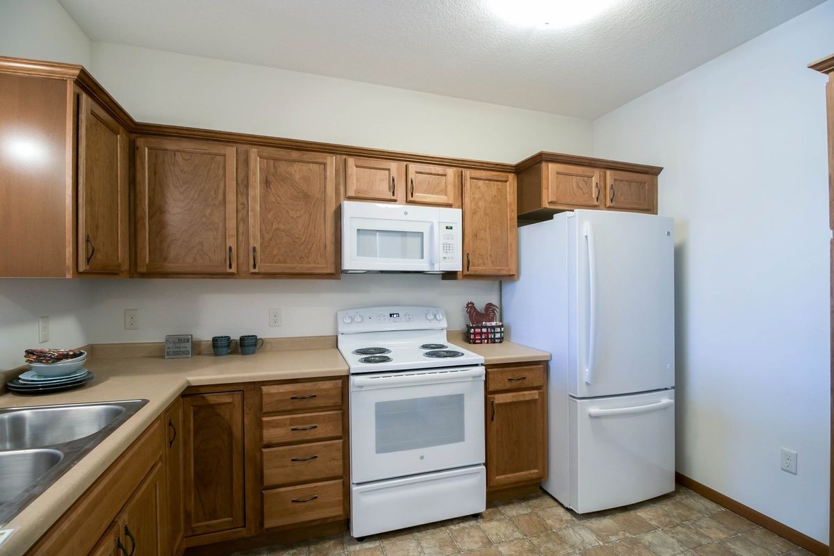 A kitchen featuring wooden cabinets, a white refrigerator, stove, and microwave.