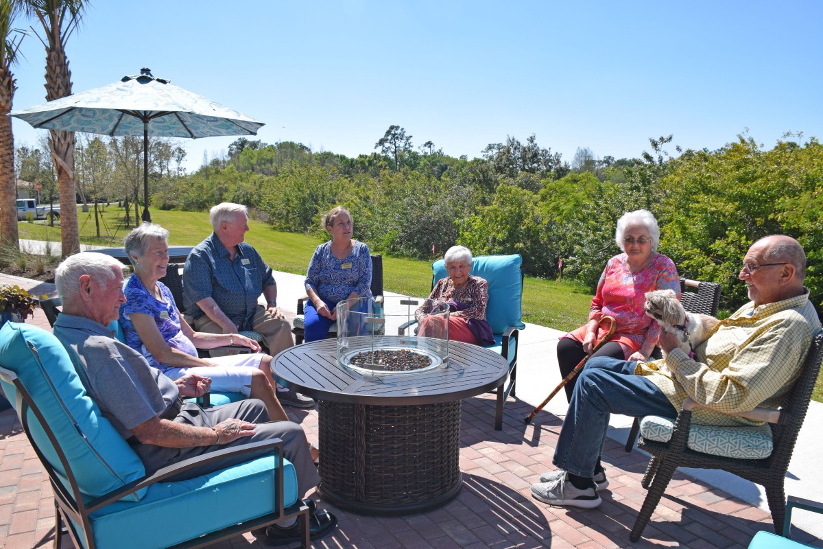A group of people sitting outside enjoying a sunny day and engaging in conversation.