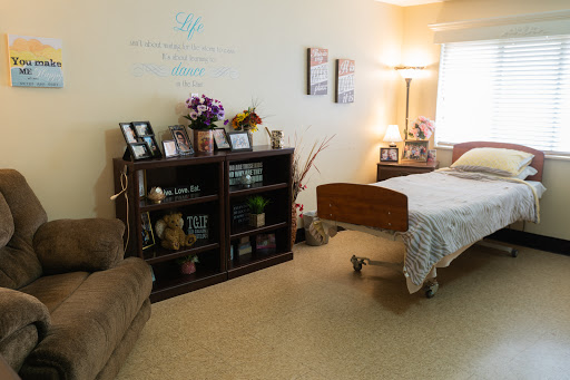 A cozy bedroom setup featuring a hospital bed, decorative shelf, and comfortable seating.