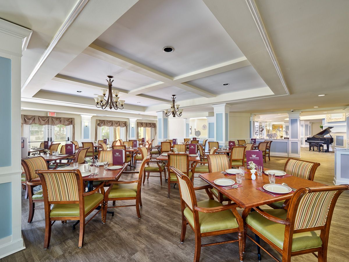 A spacious and elegantly designed restaurant dining area with wooden tables, comfortable chairs, and ornate chandeliers.