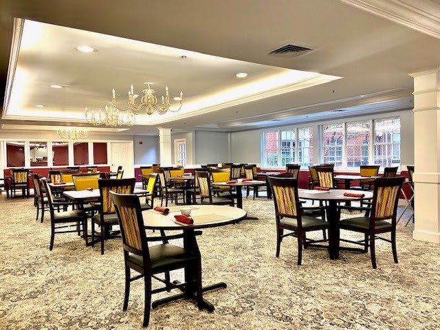 Spacious dining area with elegant chandeliers and neatly arranged tables and chairs.