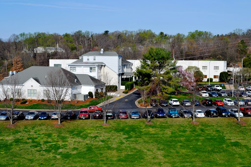 Aerial view of a residential area featuring buildings, a parking lot filled with cars, and green grass.