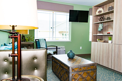 A modern living room featuring a stylish coffee table, comfortable seating, and a television against a soothing green backdrop.