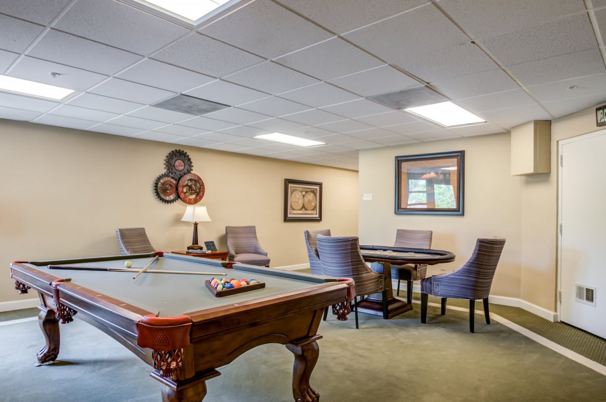 A recreational room featuring a pool table and a seating area with artwork on the walls.