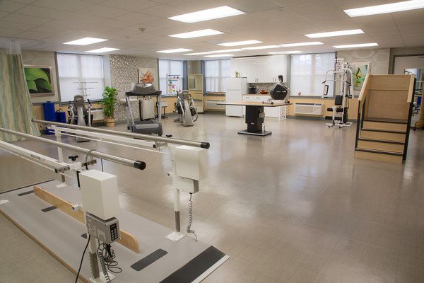 A spacious rehabilitation room equipped with various exercise machines and therapy equipment.