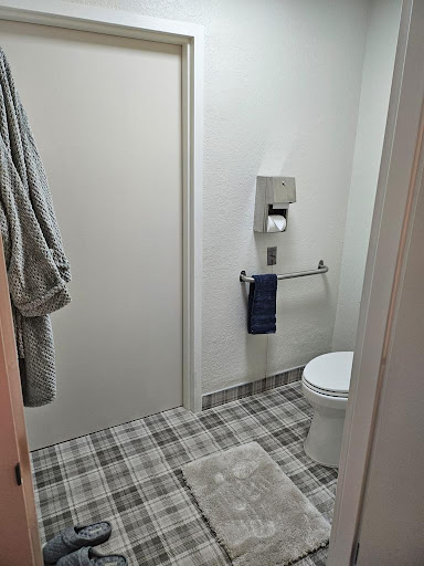 A simple and clean bathroom setup featuring a toilet, towel rack, and plaid flooring.