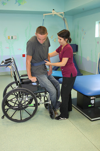 A healthcare professional assisting a patient in a wheelchair during a rehabilitation session.