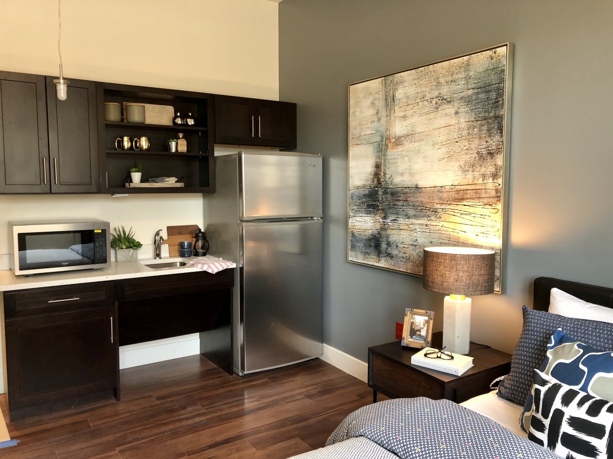A modern studio apartment featuring a compact kitchenette and stylish decor.