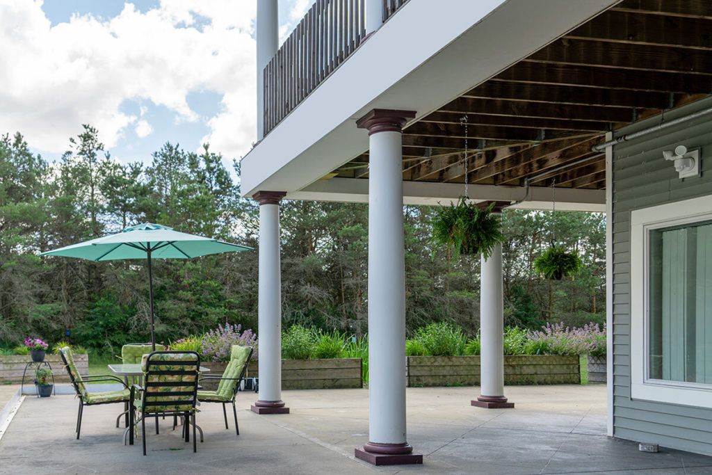 A spacious outdoor patio featuring columns and patio furniture under a clear sky.
