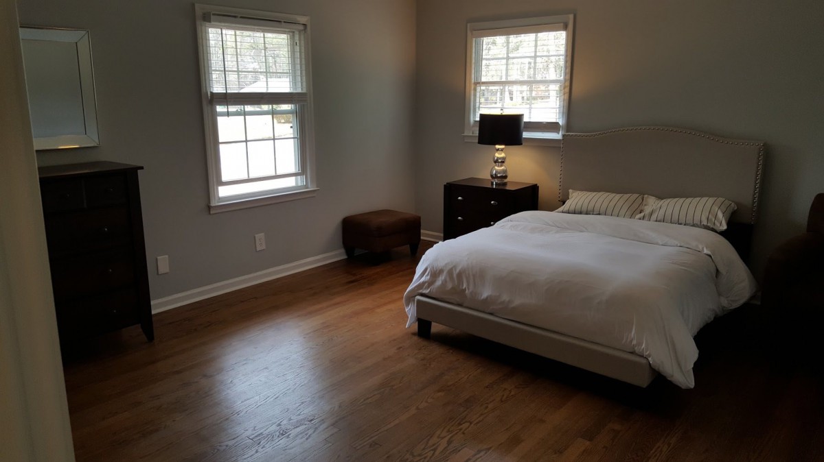 A minimalist bedroom with wooden flooring and simple furnishings.