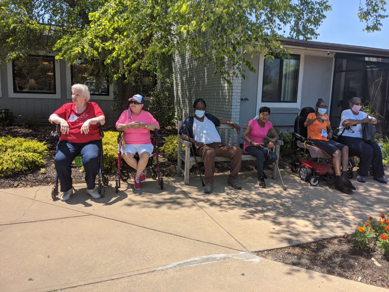A group of people sitting on benches outdoors on a sunny day.