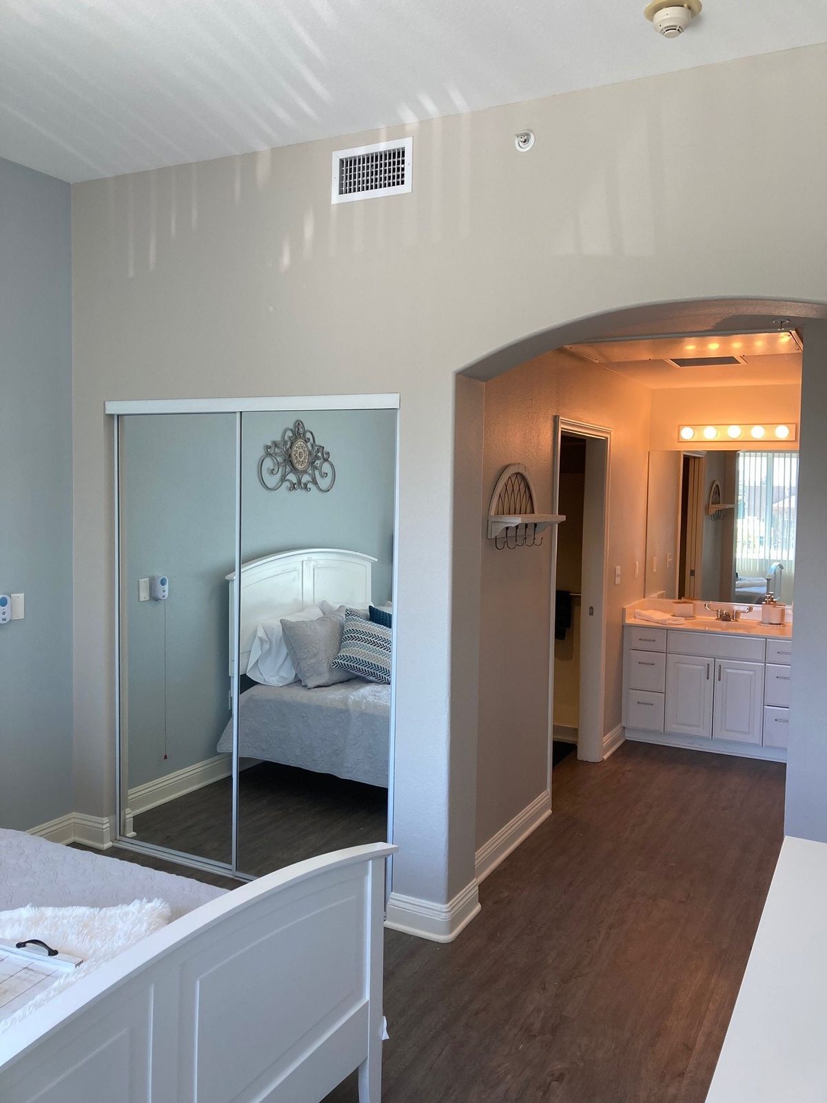 A bright bedroom with a mirrored closet and an attached vanity area.