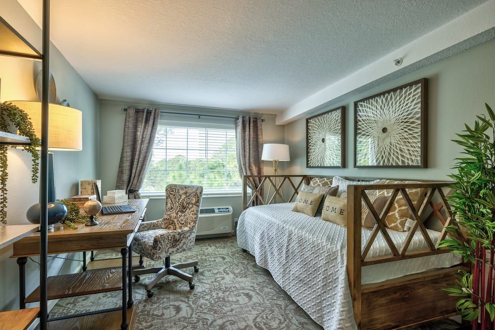 A cozy bedroom with a desk setup, featuring stylish decor and natural light.