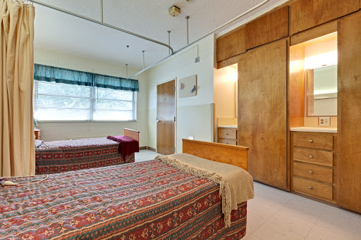 A cozy bedroom featuring two beds with patterned covers and warm wooden accents.